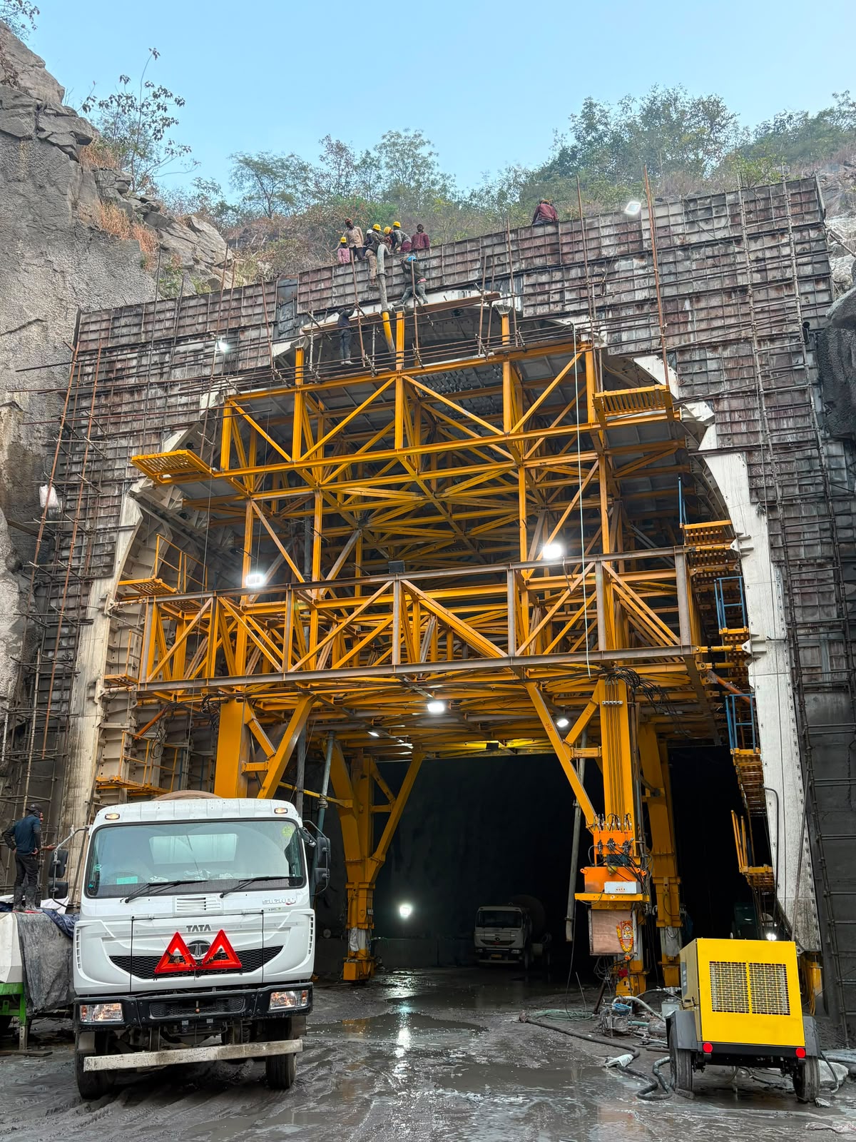 Yellow gantry formwork at a tunnel portal with concrete truck on site